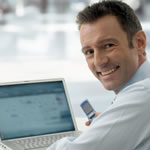 Man at laptop with cell phone