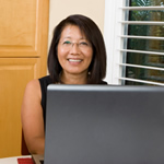 Adult learner at her desk with her laptop smiling.
