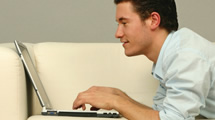 Man using laptop to study on a couch - minnesota school of business online